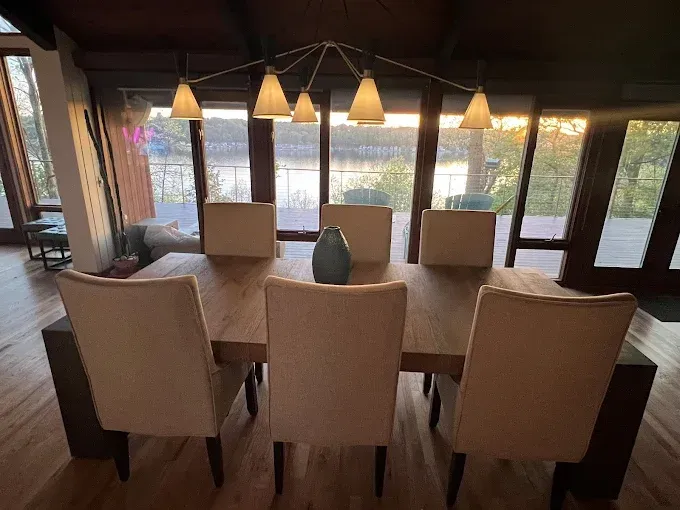 A dining room table with chairs and a vase on it.