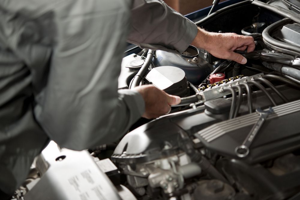 A man is working on a car engine with a wrench.