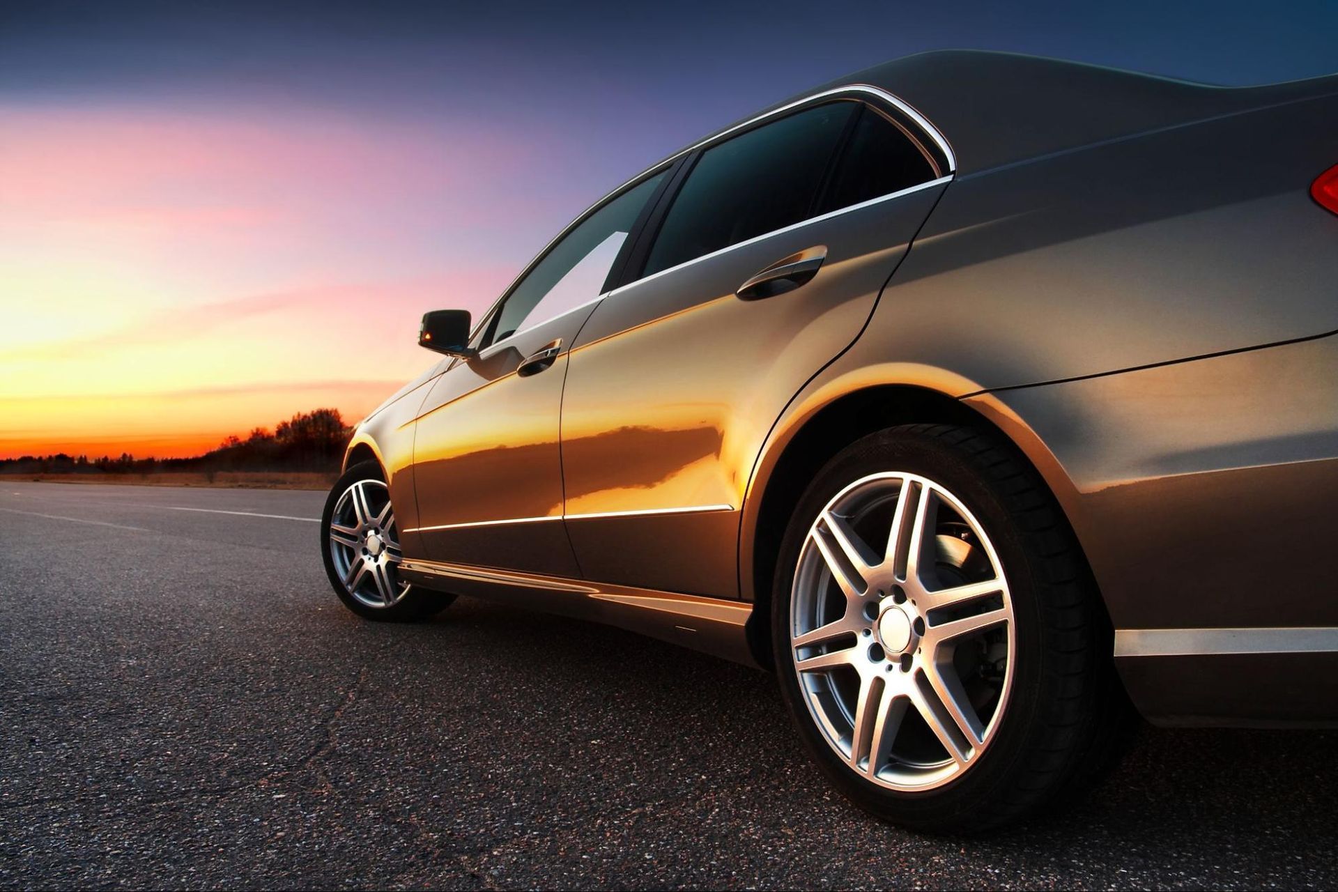 A car is parked on the side of the road at sunset