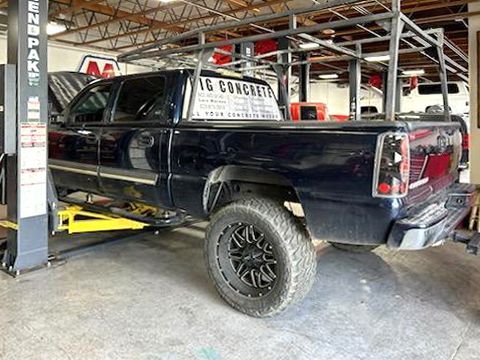 A black truck is parked on a lift in a garage.