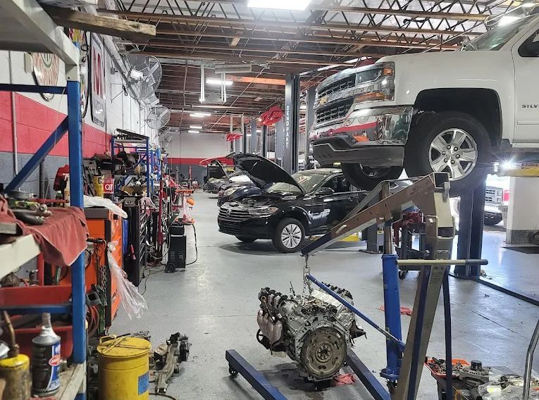Auto repair shop: truck on lift, engine on stand, tools, vehicles, shop interior.