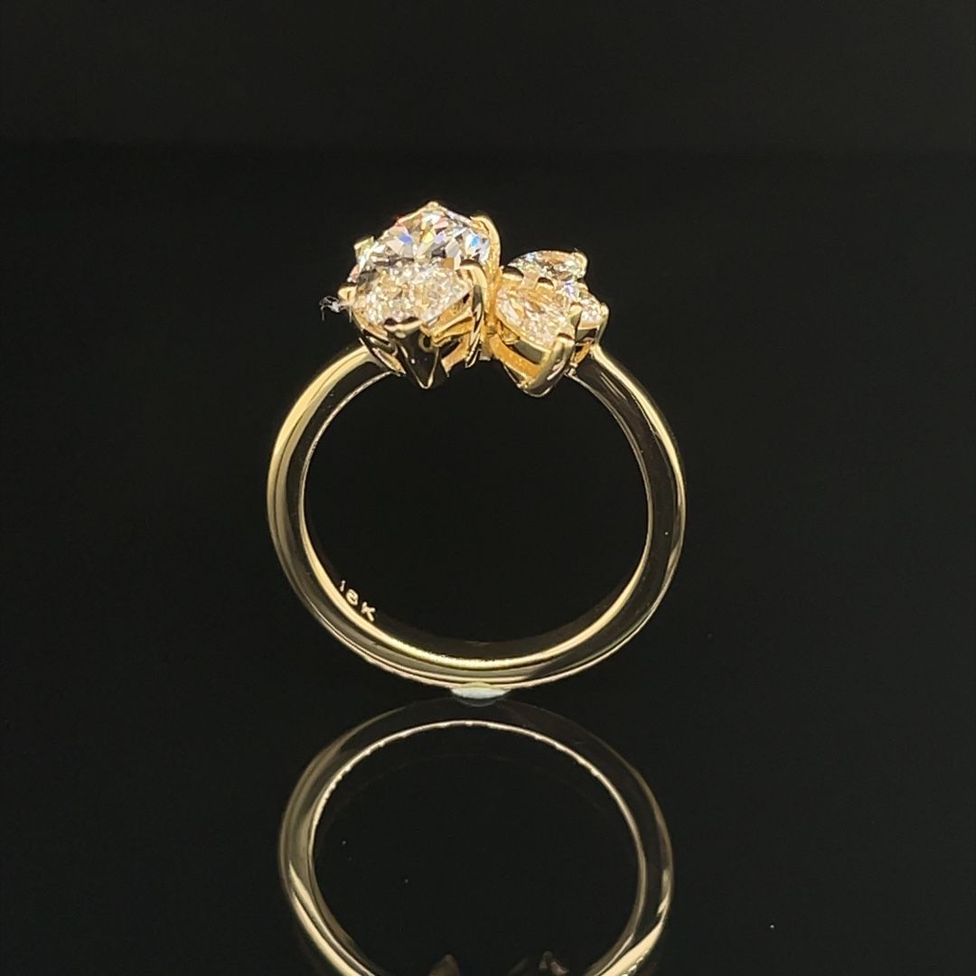 A gold ring with two diamonds on a black surface
