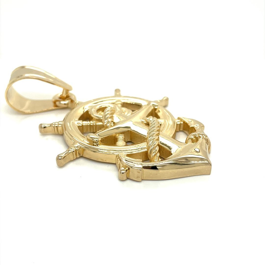 A gold pendant in the shape of a steering wheel and anchor