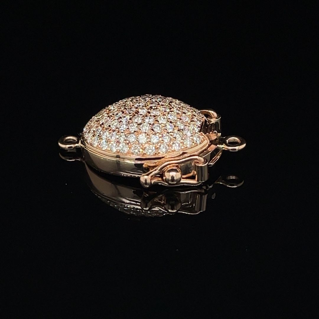 A close up of a gold pendant with diamonds on a black surface.