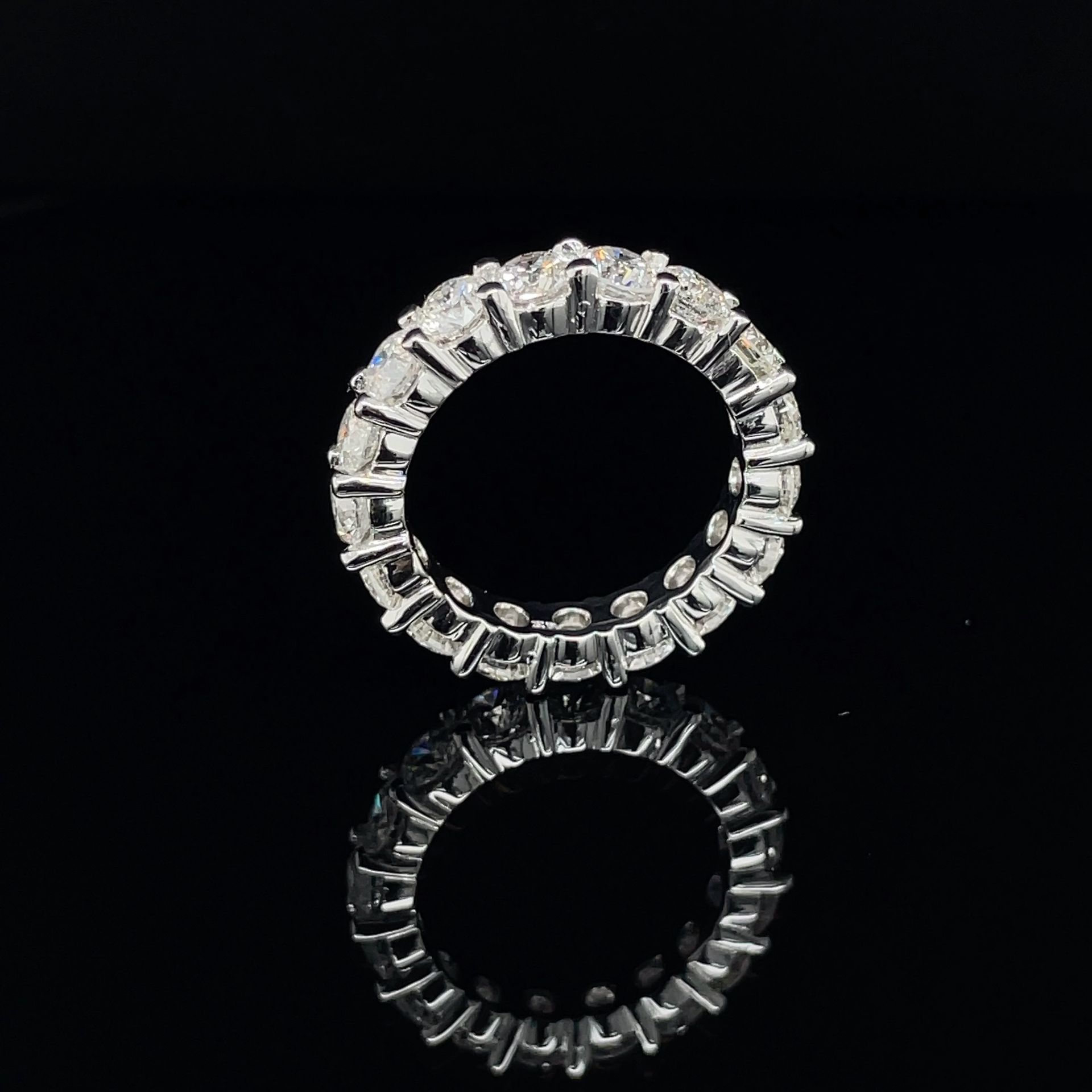 A close up of a ring with diamonds on a black surface.