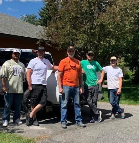 A group of men are posing for a picture in front of a truck.