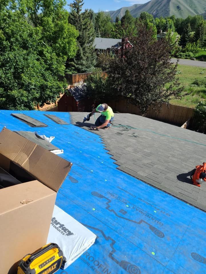 A man is laying on a blue tarp on top of a roof.