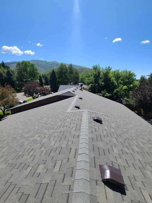 A roof with a blue sky and trees in the background
