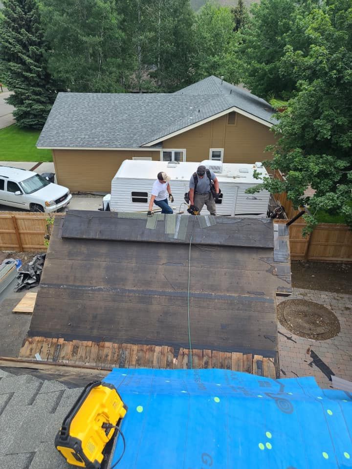 Two men are working on the roof of a house.