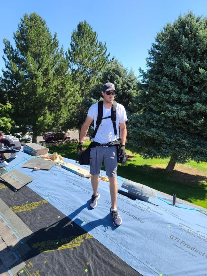 A man is standing on top of a roof with a backpack.
