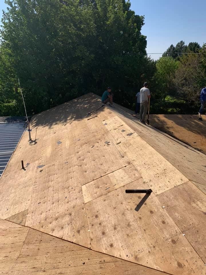 A man is standing on top of a wooden roof.