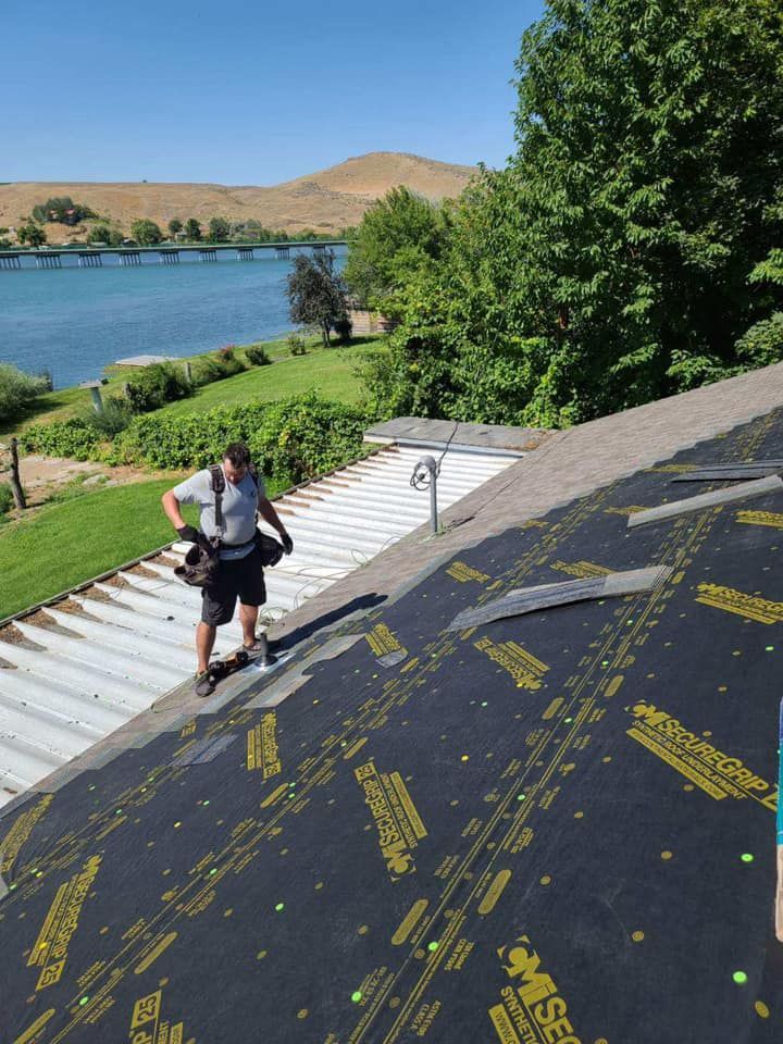 A man standing on top of a roof with a lake in the background