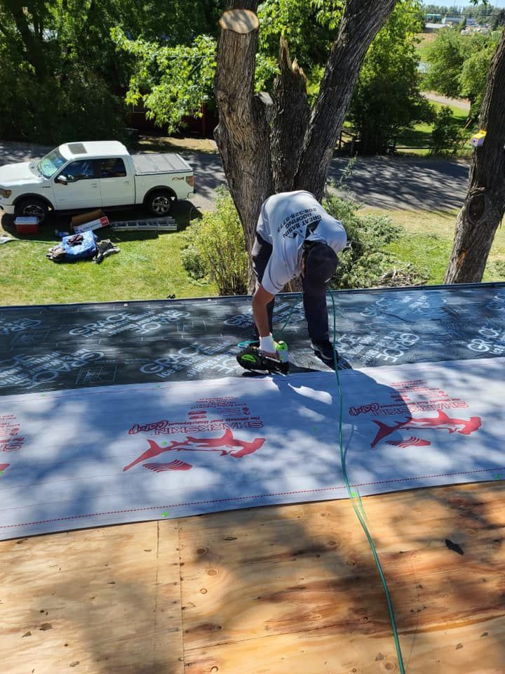 A man is working on a roof with a truck in the background.