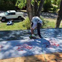 A man is working on a roof with a truck in the background.