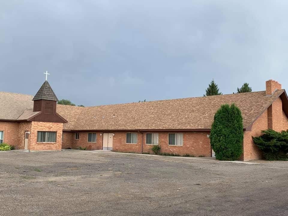A large brick building with a steeple and a cross on top of it.