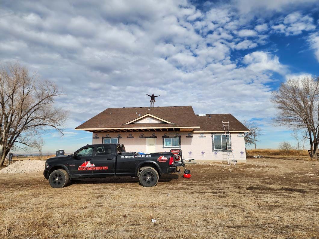 A black truck is parked in front of a house in a field.