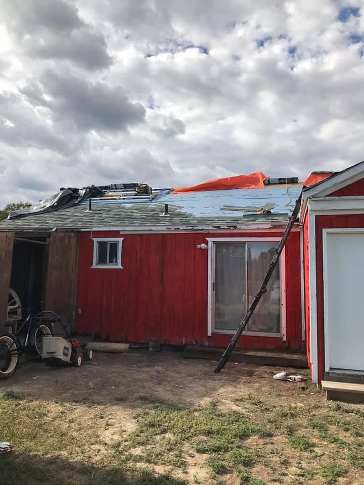 A red house with a roof that is being repaired.