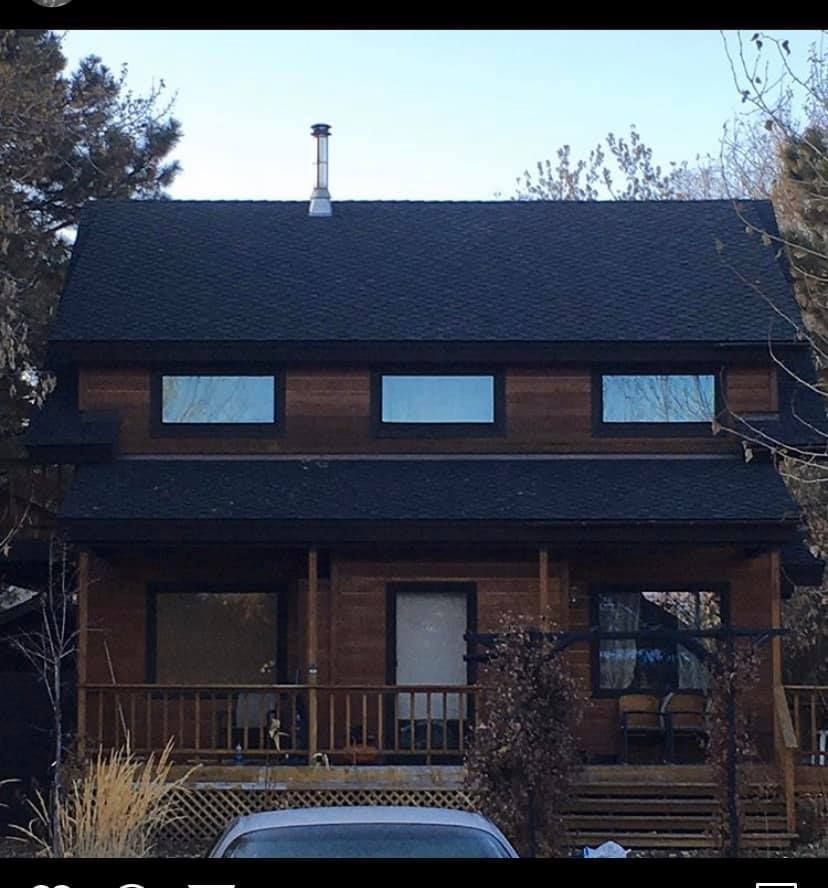 A car is parked in front of a house with a black roof