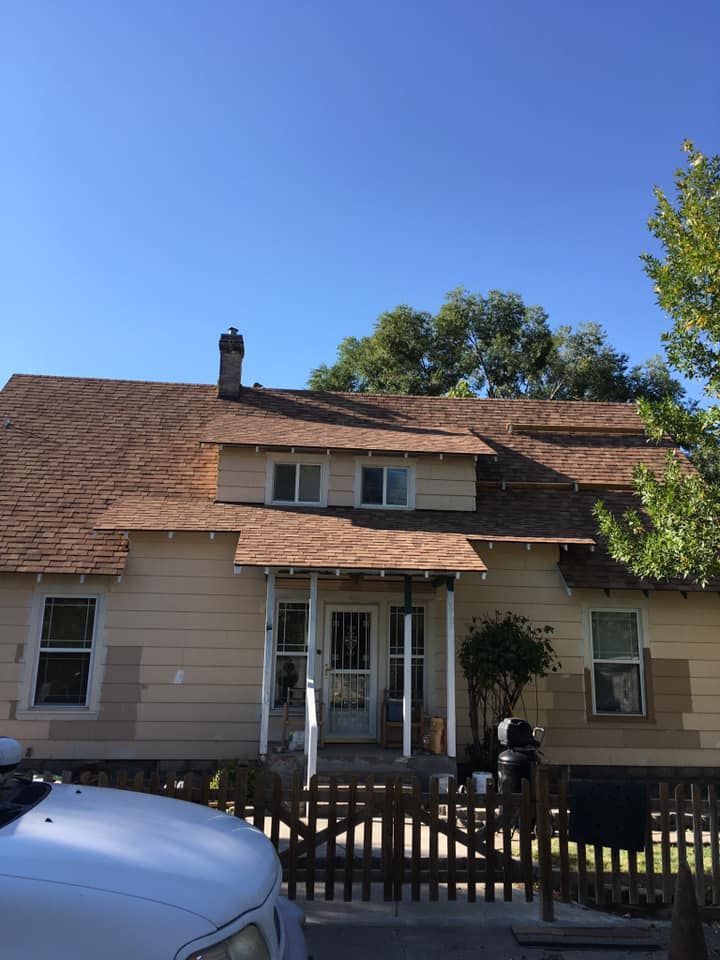 A white truck is parked in front of a house with a brown roof.