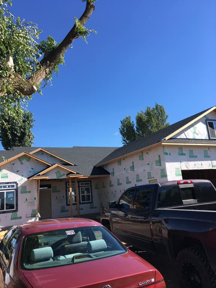 A red car is parked in front of a house under construction