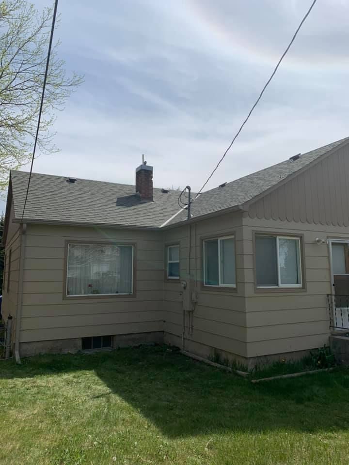 The back of a house with a roof and a chimney.