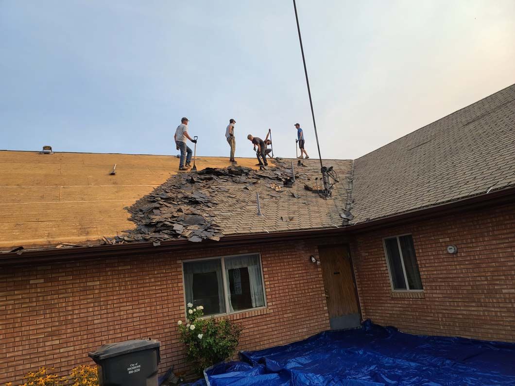 A group of people are working on the roof of a brick house.