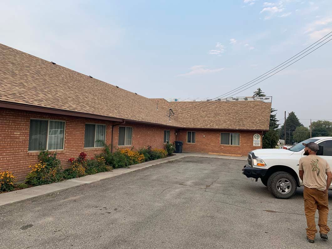 A man is walking towards a white truck parked in front of a brick building.