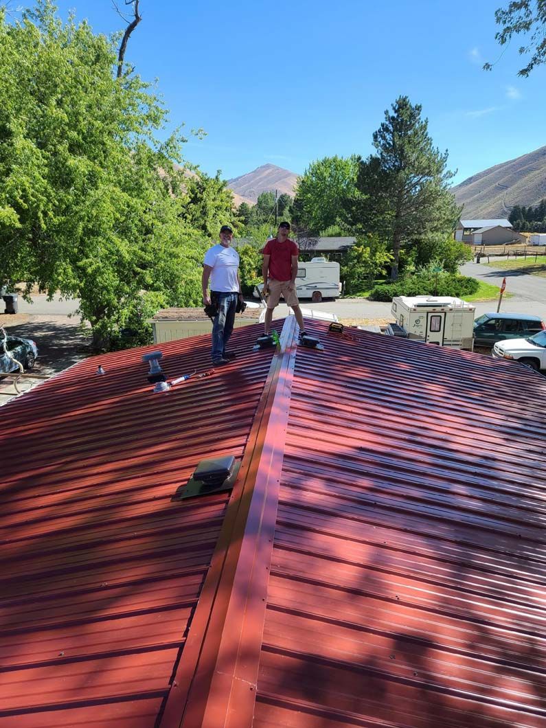 Two men are standing on top of a red roof.