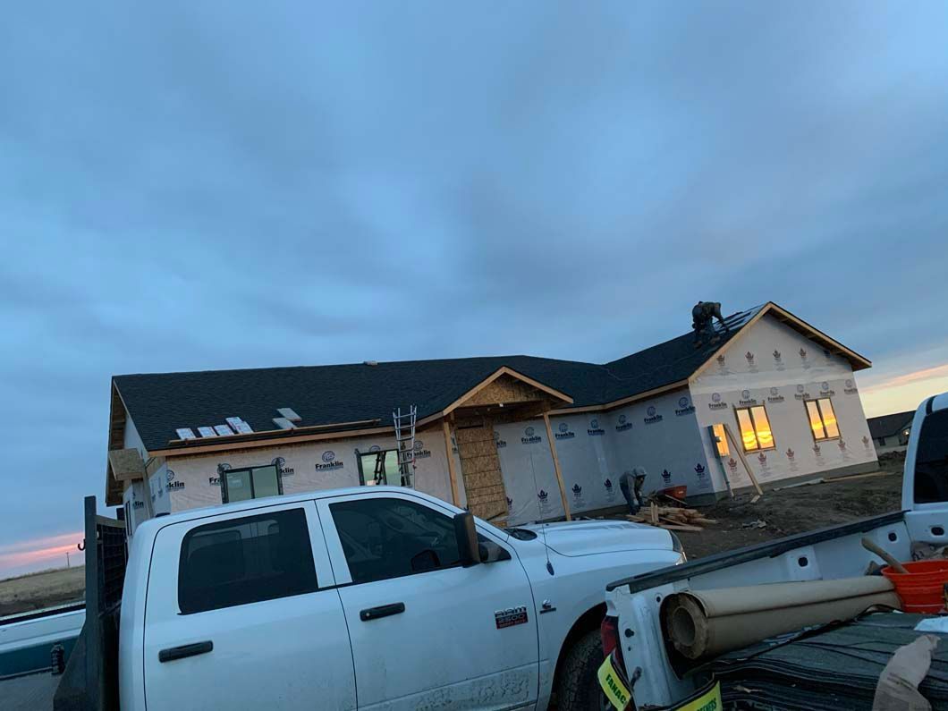 A white truck is parked in front of a house under construction.