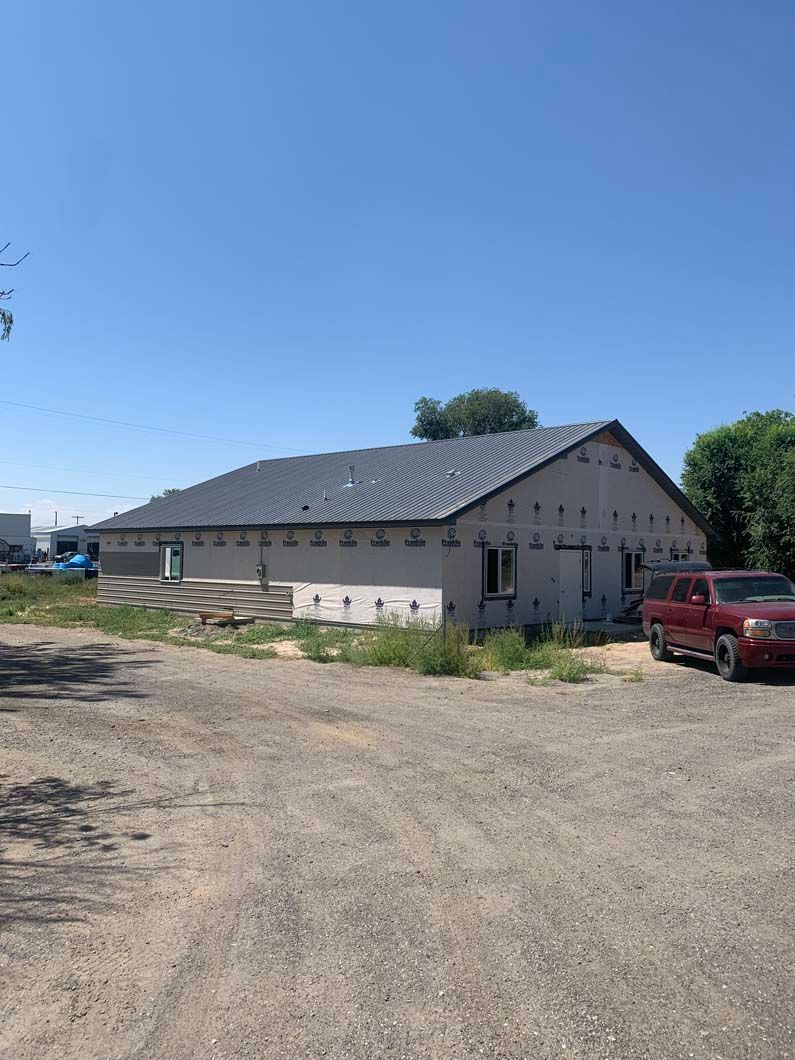 A red truck is parked in front of a building under construction.