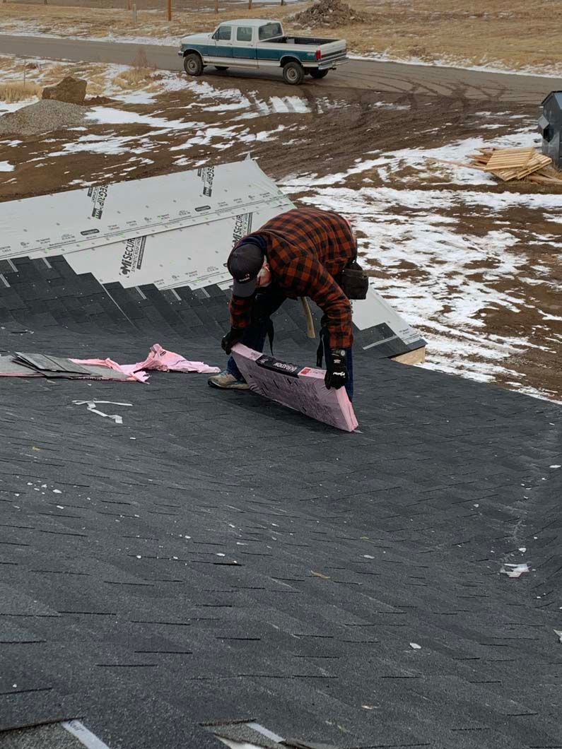 A man is working on a roof in the snow.