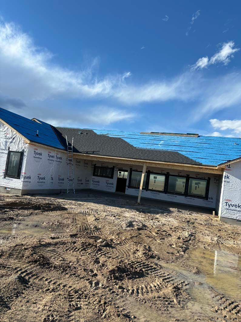 A house under construction with a blue tarp on the roof.