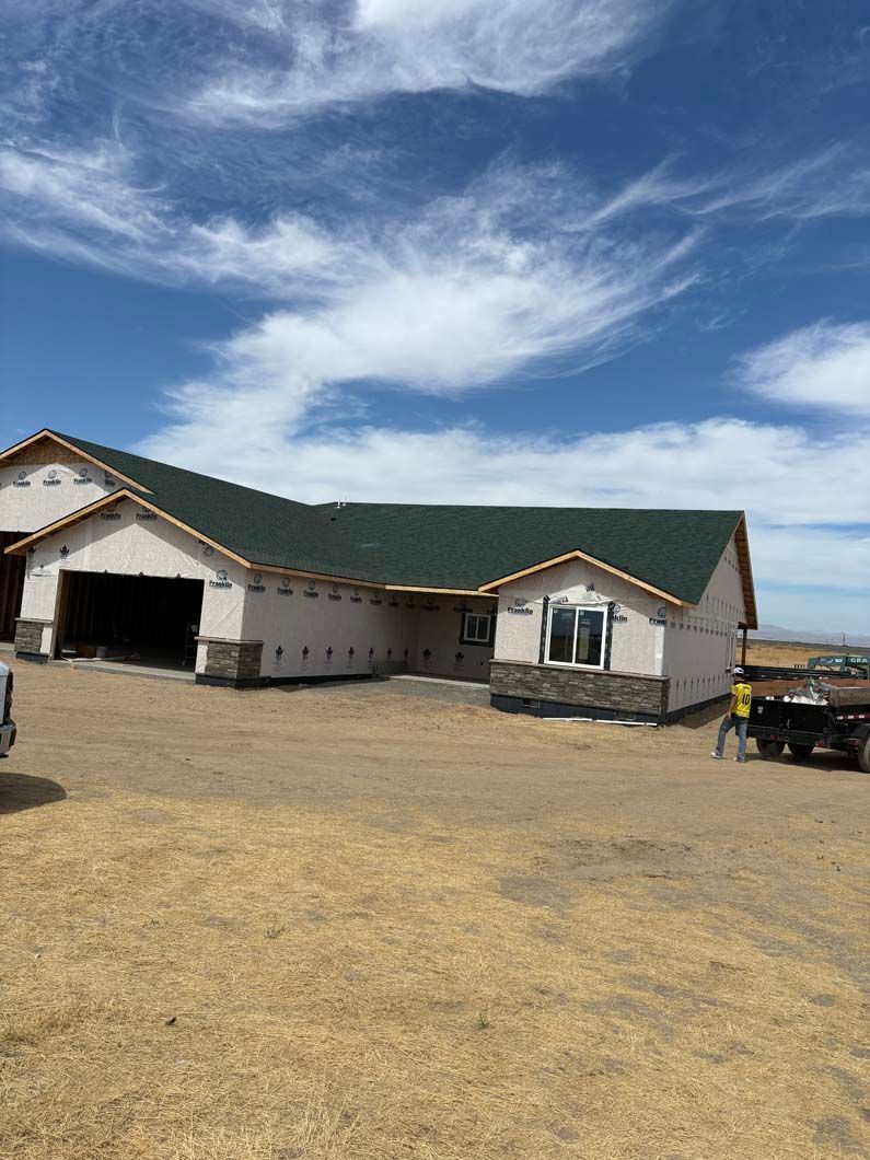 A large white house with a green roof is being built.