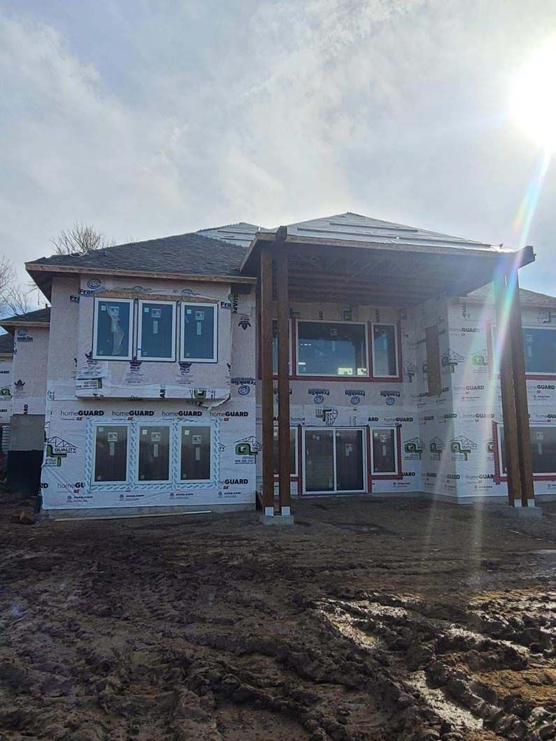A large house is being built in the middle of a dirt field.