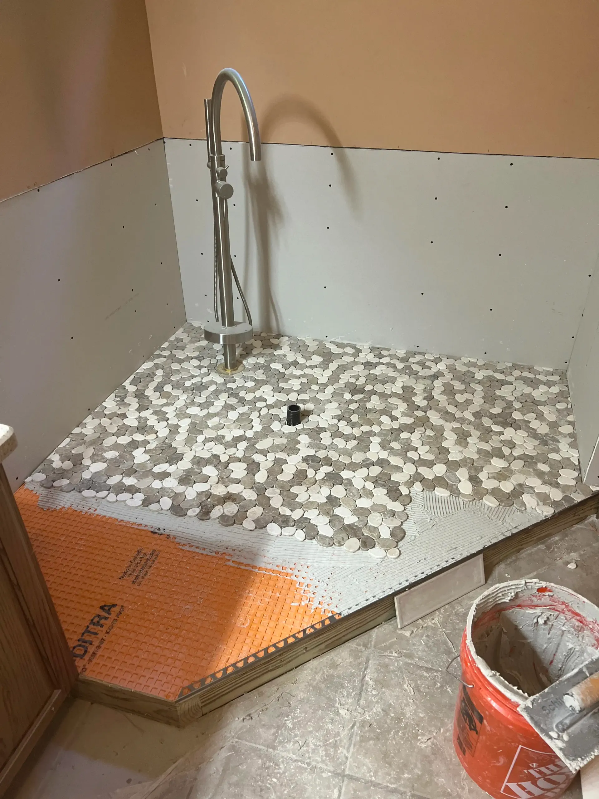 Two chairs and a small table arranged beneath a wall-mounted fireplace on a dark accent wall in a room with wood flooring.