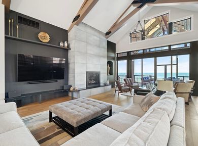 A view through an open doorway into a room with gray wood-look flooring, dark cabinetry, and a wall-mounted fireplace.