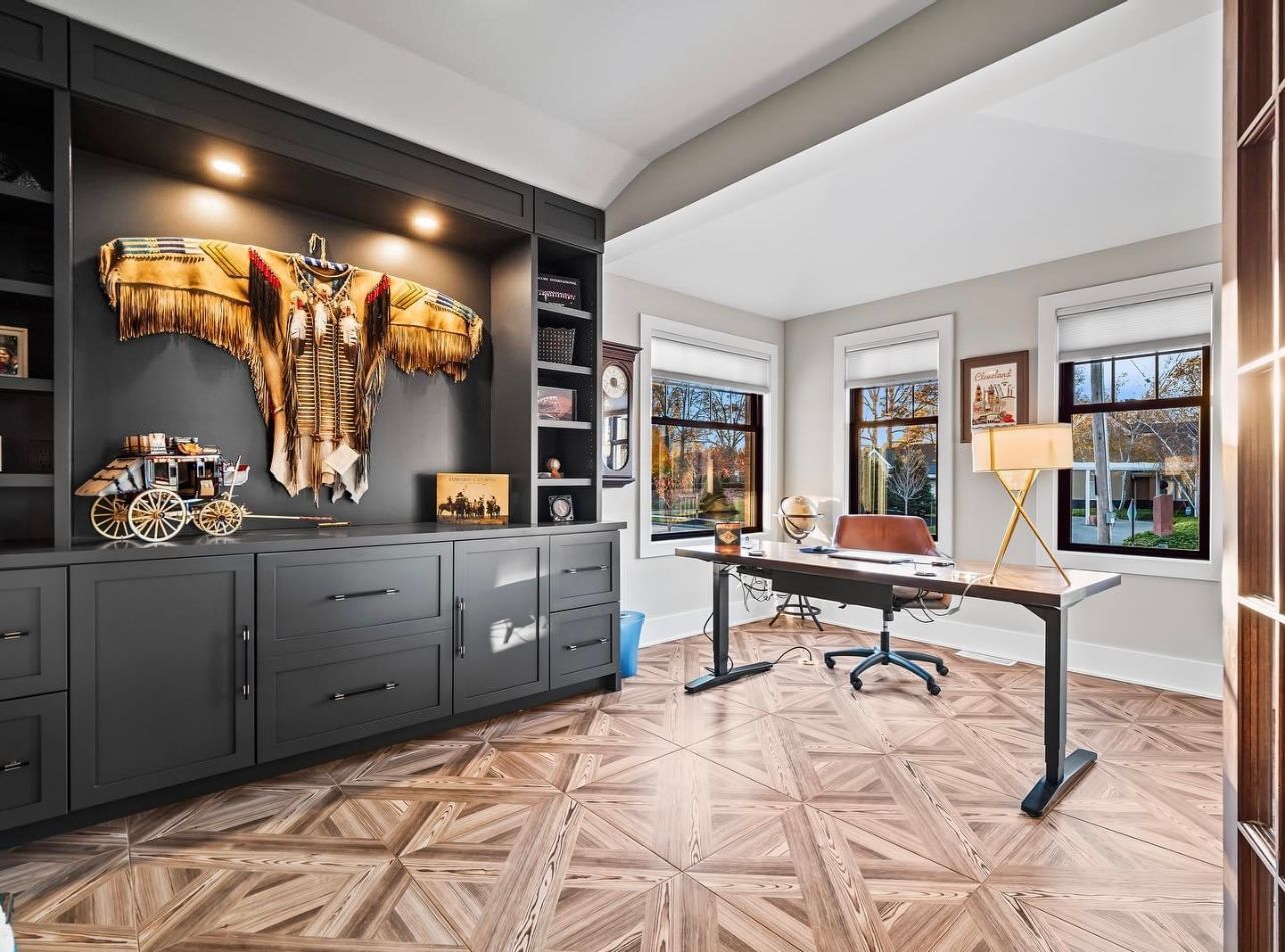A doorway opens into a room with wood-look flooring, a black feature wall with an electric fireplace, and framed artwork.