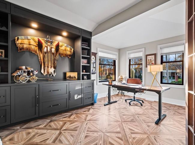 A doorway opens into a room with wood-look flooring, a black feature wall with an electric fireplace, and framed artwork.