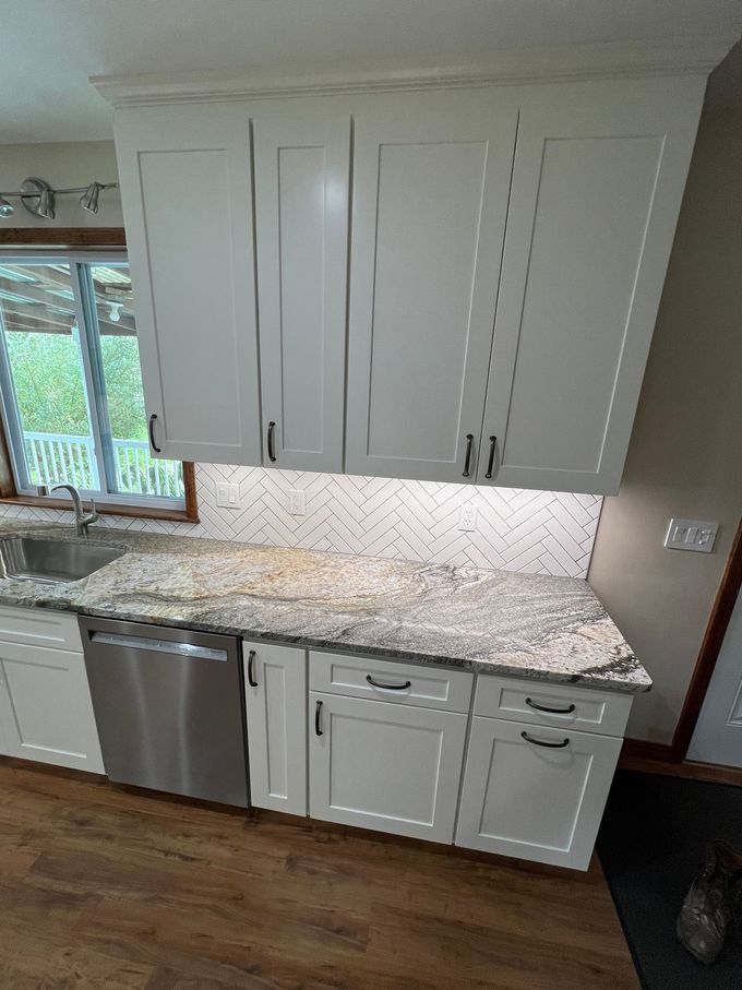 Before and after photos of a bathroom showing a tub surround renovation with marble-patterned tiles replacing old tiles.