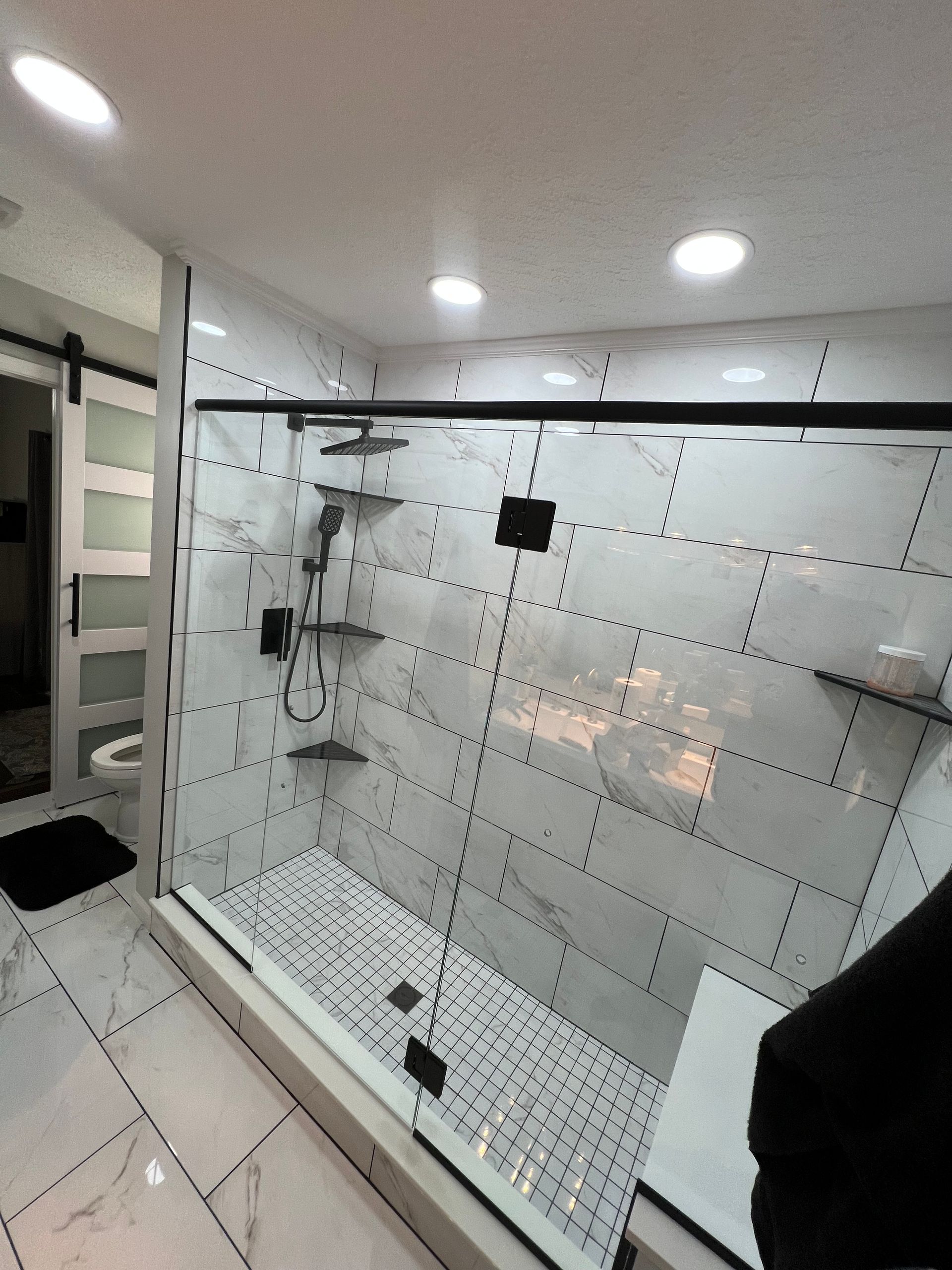 Two chairs and a small table arranged beneath a wall-mounted fireplace on a dark accent wall in a room with wood flooring.