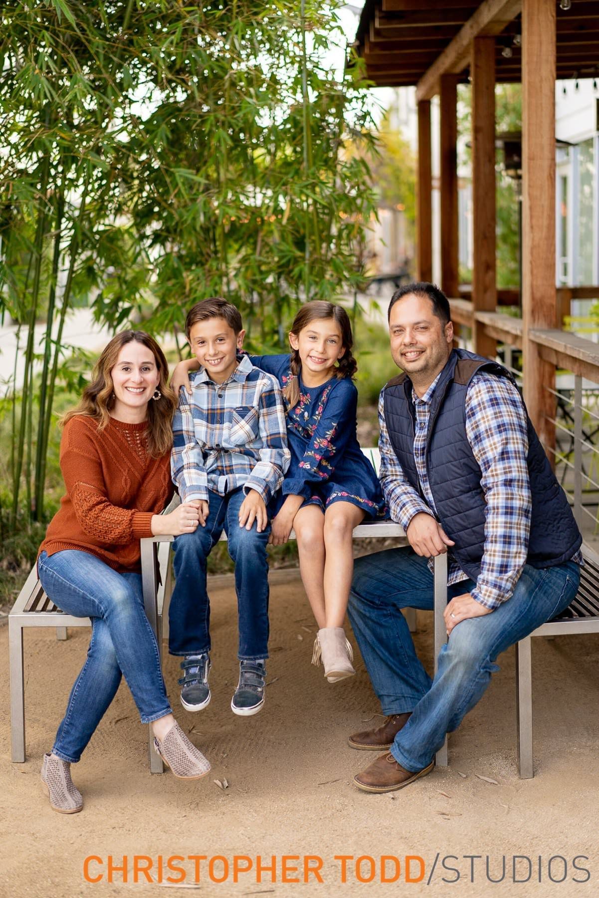 Costa Mesa Mini Session A family is posing for a picture while sitting on a bench in Costa Mesa.