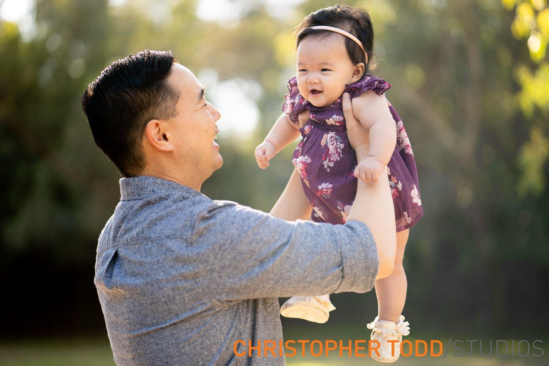 Huntington Beach Mini Session A man is holding a baby in his arms during the fall mini session at Orange County park.