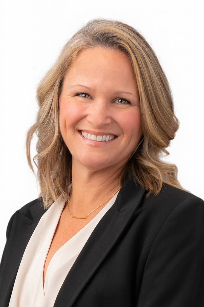 A woman in a black jacket and white shirt is smiling for the camera.