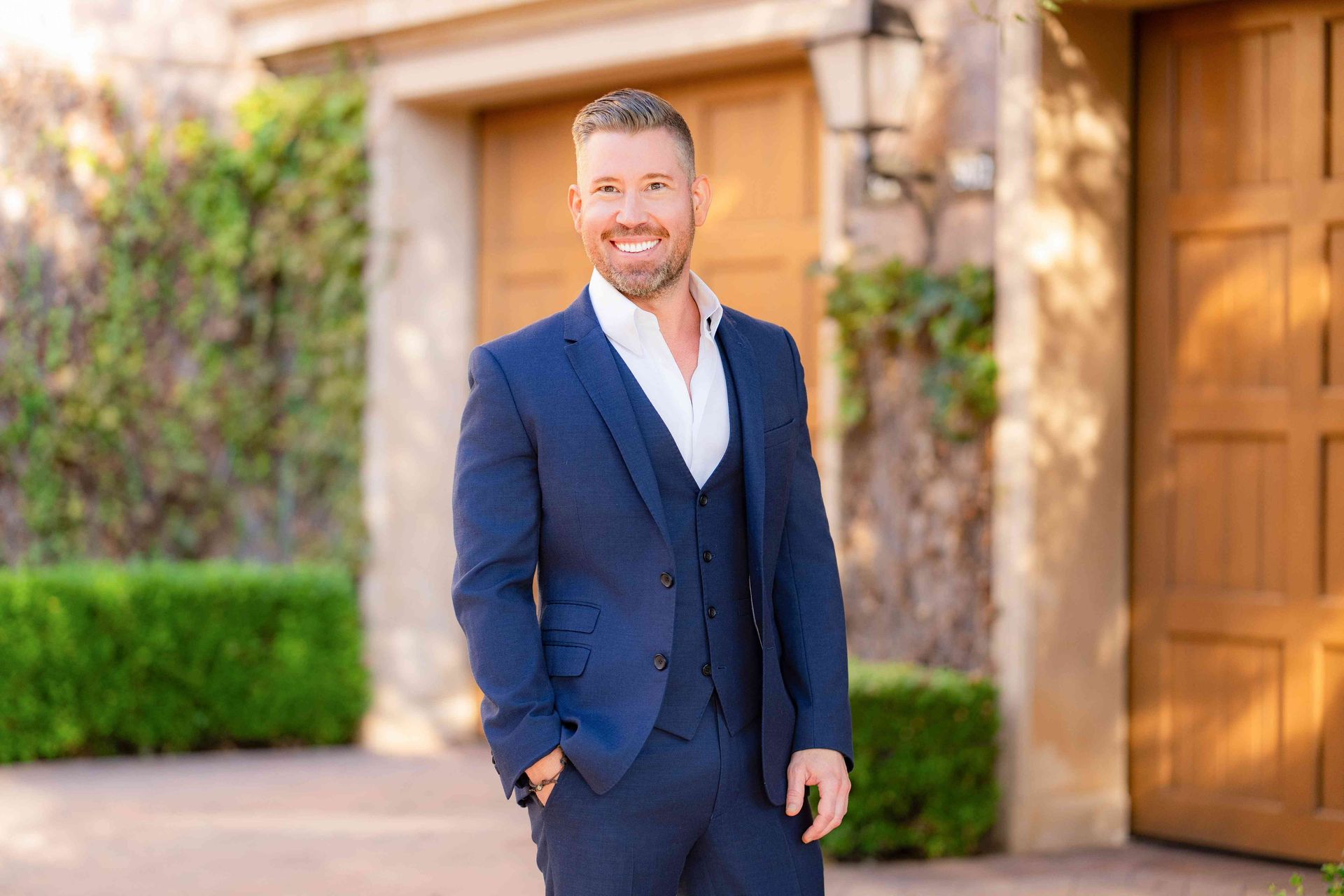 Dana Point Realtor Photographer A man in a suit is standing in front of a house with his hands in his pockets.