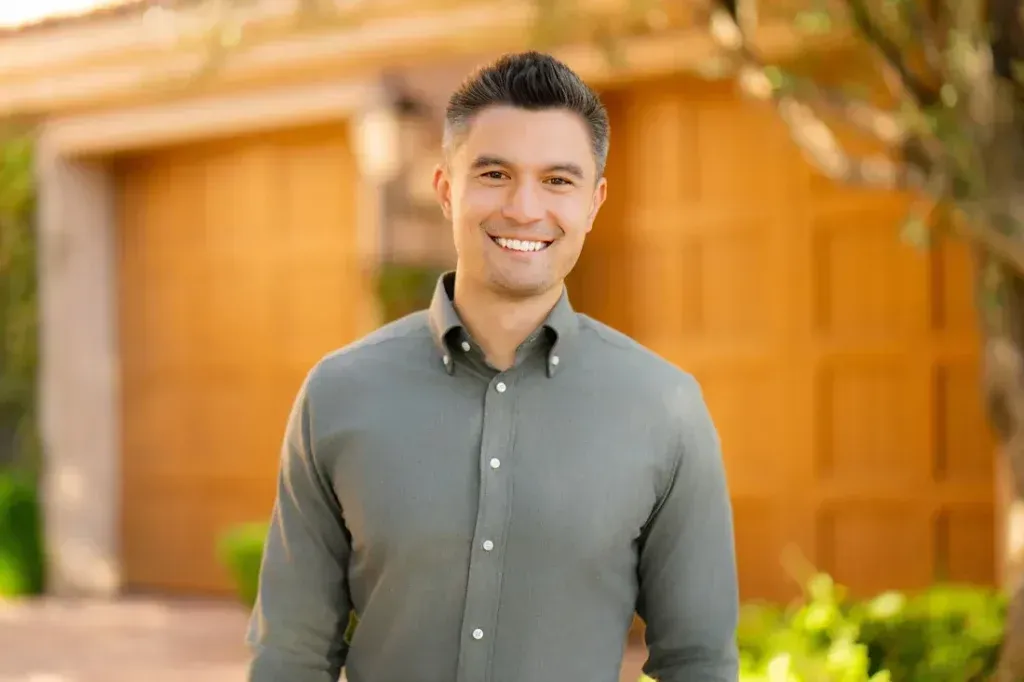 Male Headshot Example A man in a green shirt is standing in front of a house.