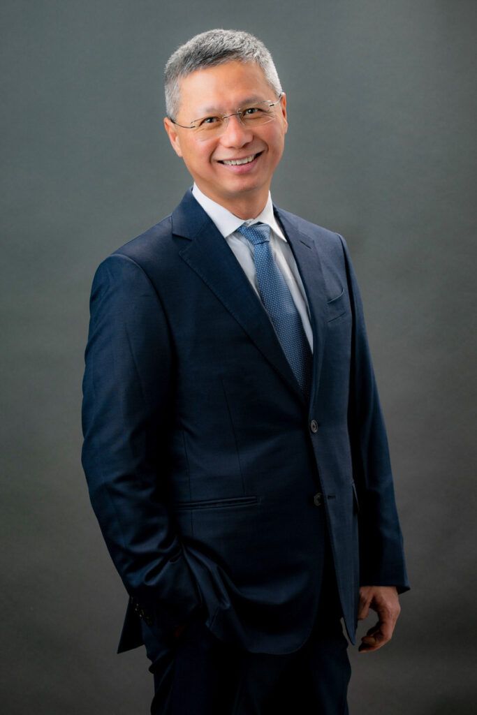 A man in a suit and tie is standing with his hands in his pockets.