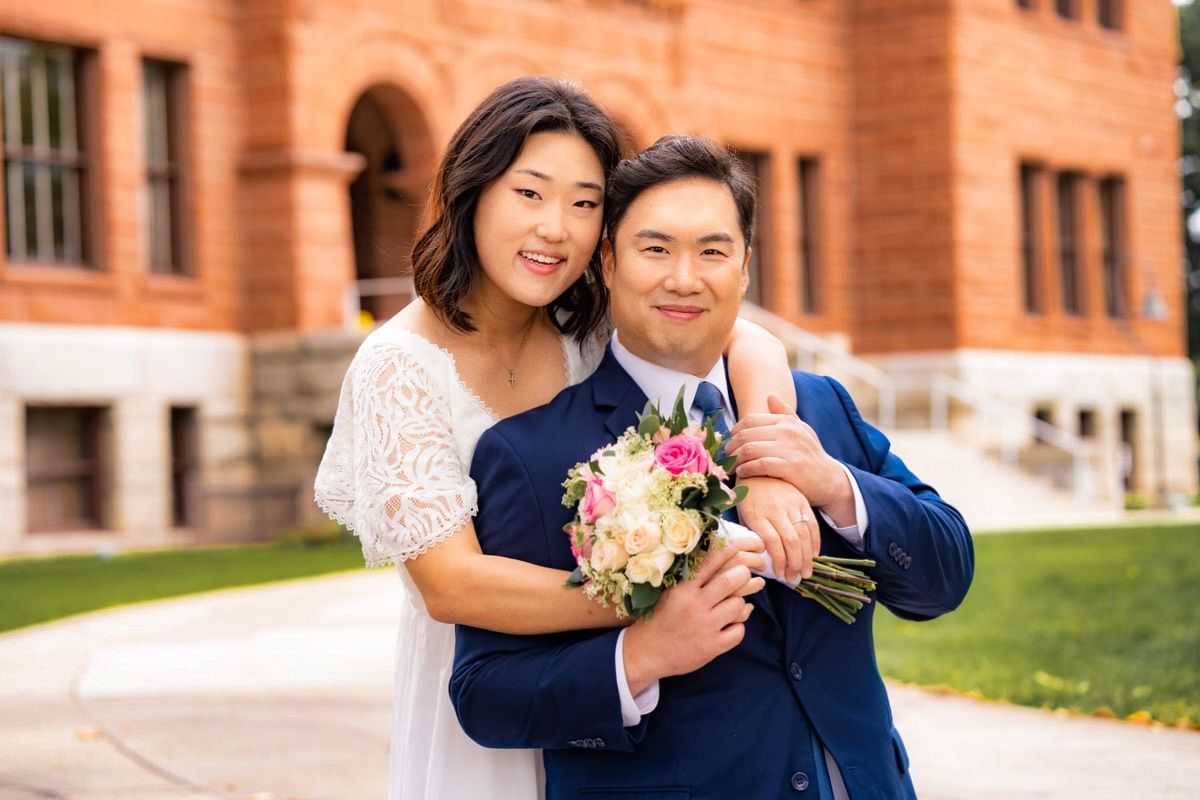 A bride and groom are posing for a picture in front of the old courthouse in Orange County
