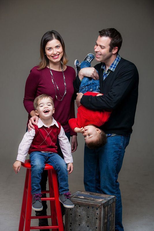 Studio Family Portrait A family is posing for a picture with two children sitting on red stools.