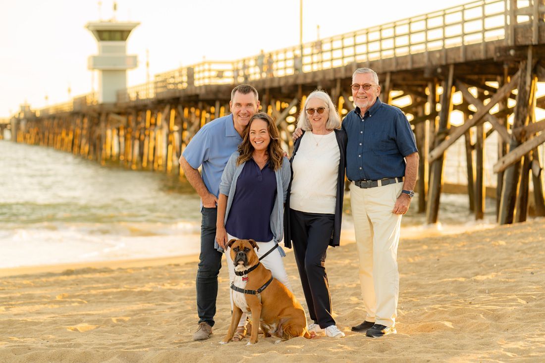 Laguna-Hills–Civic-Center A group of people and a dog are posing for a picture on the beach in front of the Balboa Pier.