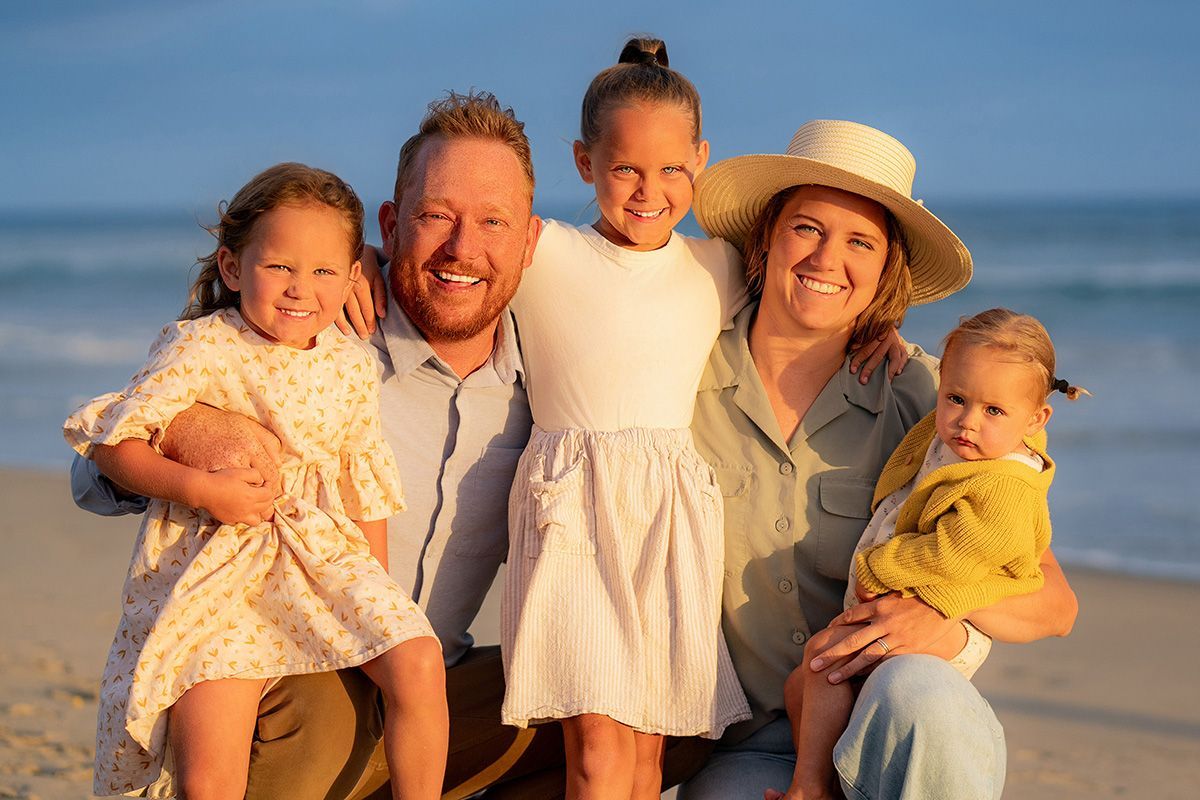 A family is posing for a picture on the beach.